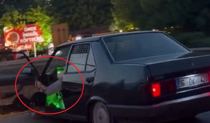 Bursa'da otomobilinin sol ön kapısını açıp, ayağıyla tutarak trafikte ilerledi